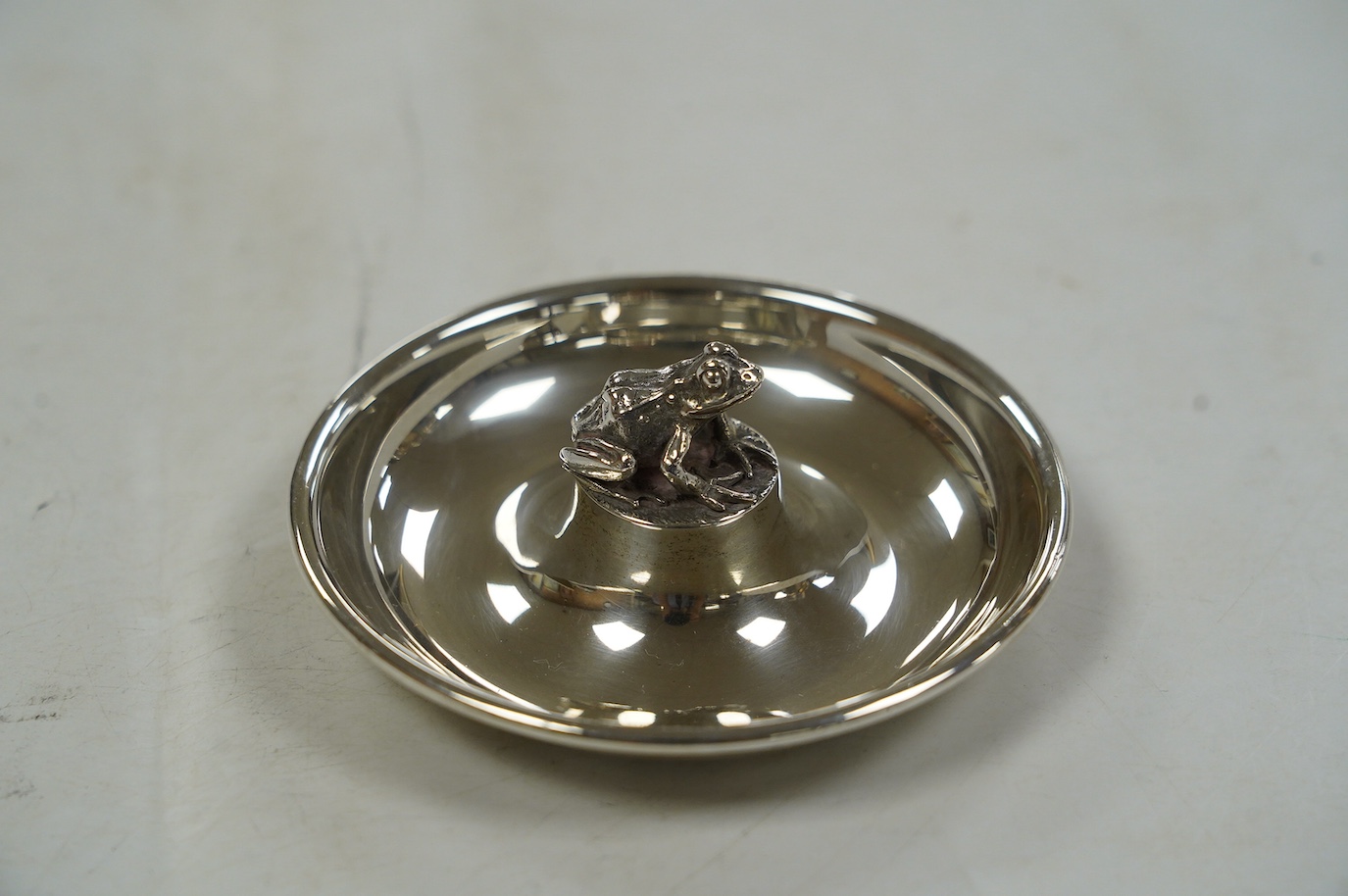 An Elizabeth II silver circular dish with central model of a frog, by Brian Leslie Fuller, London, 1996, 91mm. Condition - fair to good